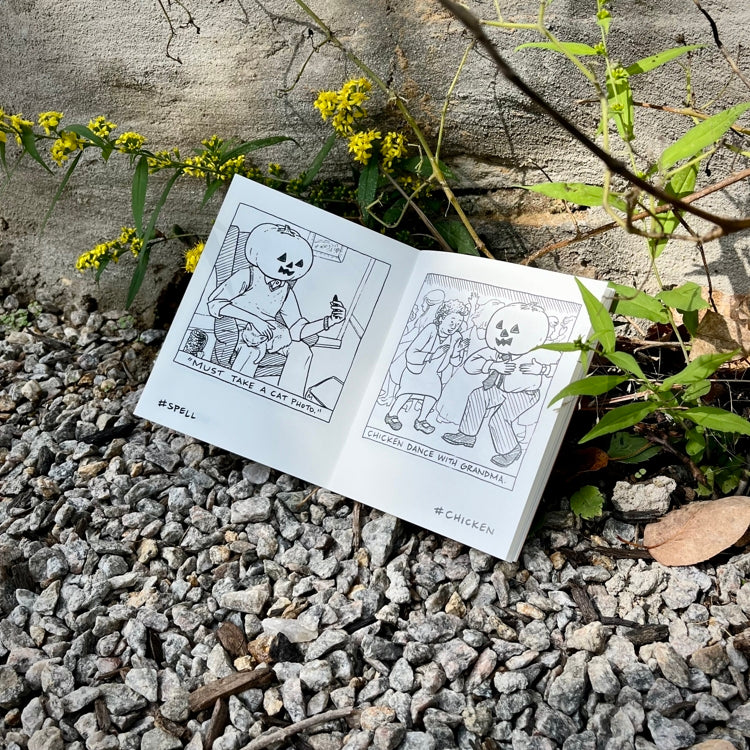 Open mini comic with black and white illustrations on a stone surface with plants.