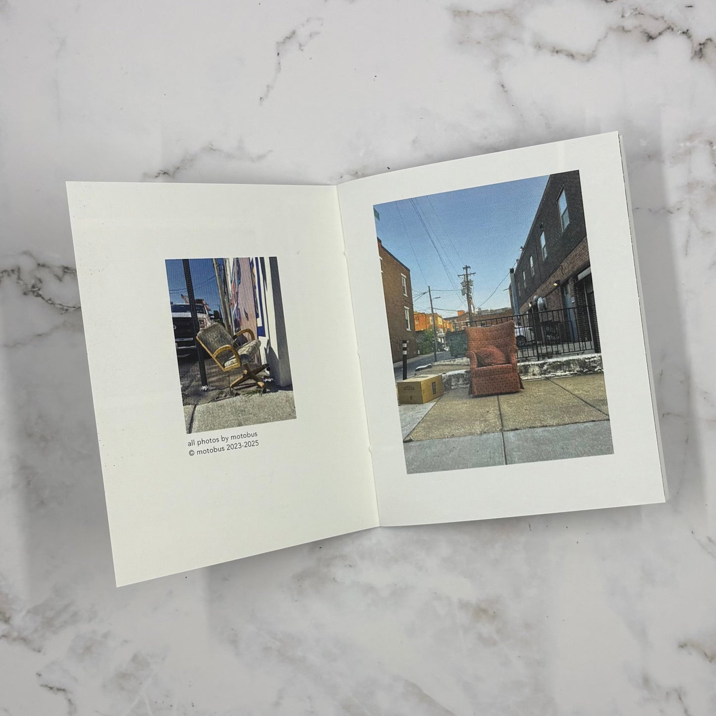 Open mini photo book on a marble surface with two images of chairs inside.