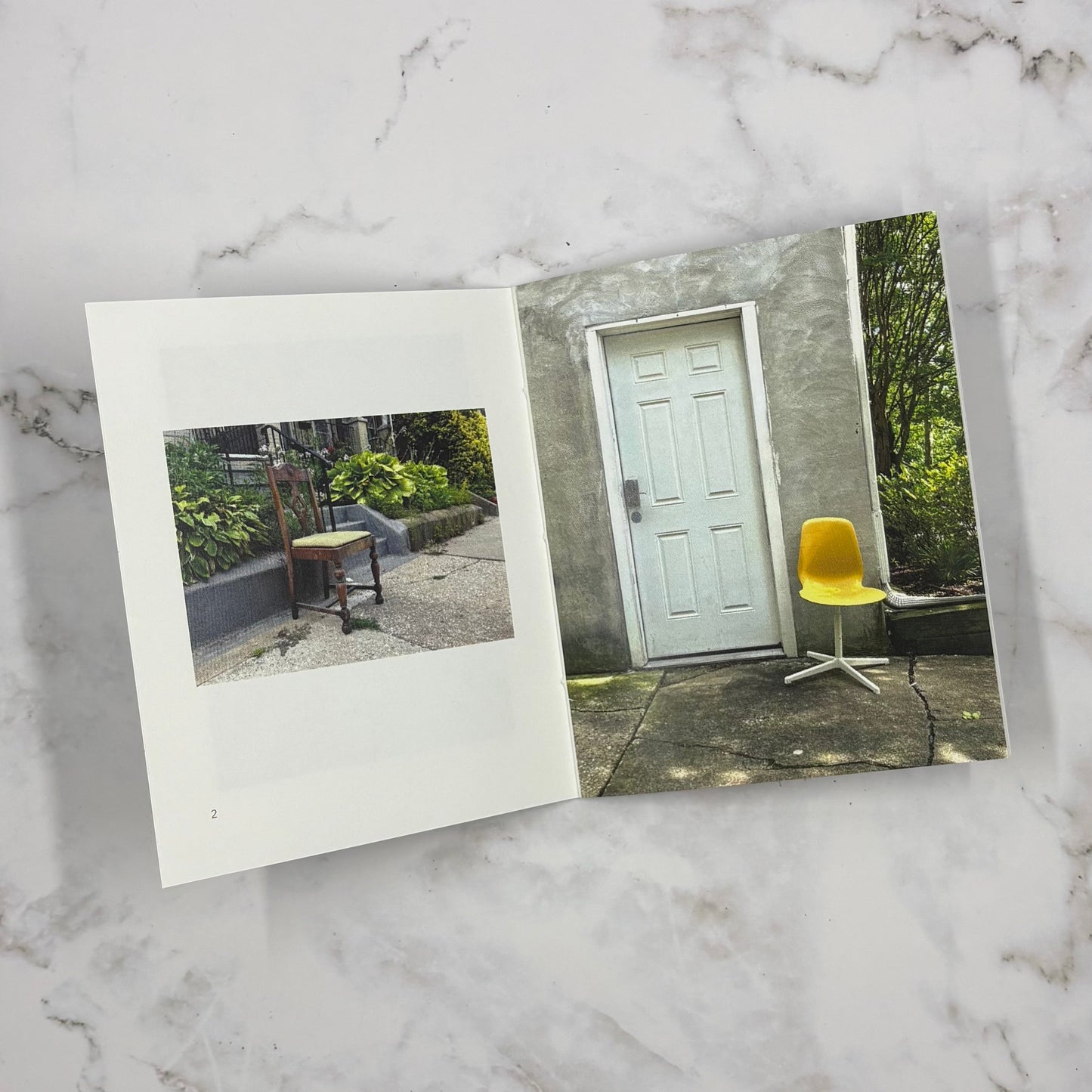 Open mini photo book on a marble surface with two images of chairs in outdoor scenes